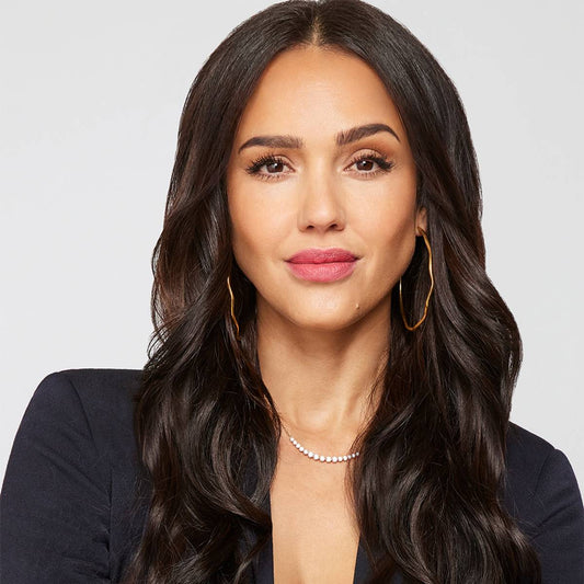 Jessica Alba wearing a black blazer with gold hoop earrings and a delicate necklace in a professional editorial portrait; styling inspiration, not Suzy Levian jewelry