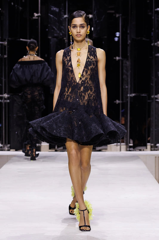 Fall-Winter 2026 Paris runway look: model wearing a long vertical yellow-gemstone necklace against a black lace dress
