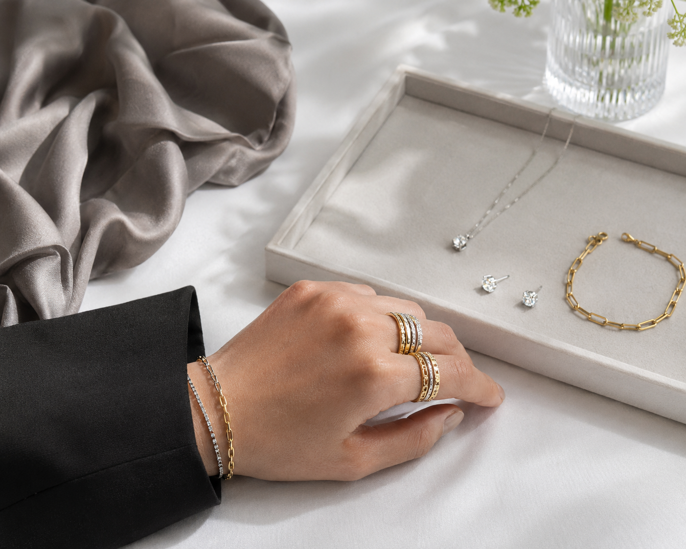 Mixed-metal jewelry styling with yellow gold and white metal rings, bracelets, earrings, and necklace on white linen