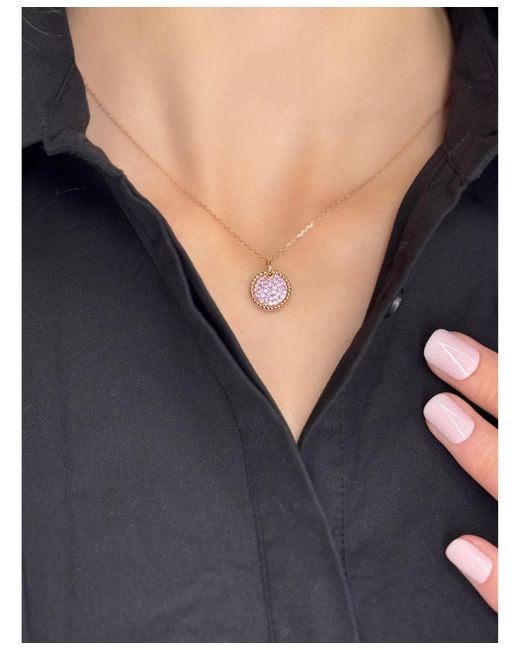 Suzy Levian pink sapphire circle pendant worn with a black collared top, showing necklace placement near the collarbone