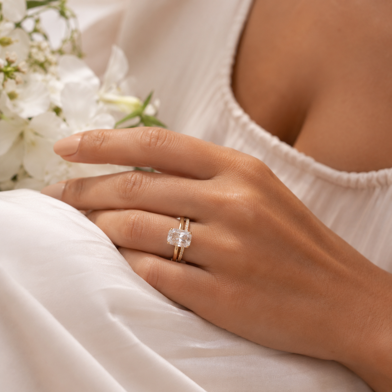 Yellow-gold engagement ring trend lifestyle image with a cushion-style center stone and soft summer bridal styling